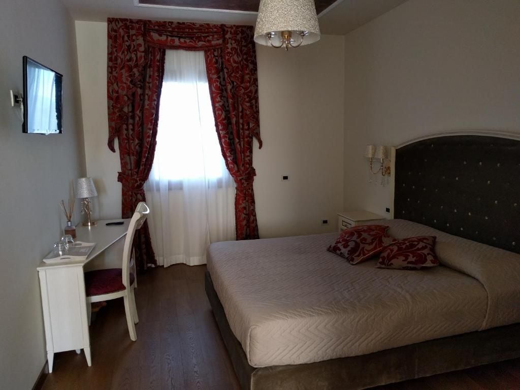 Une chambre à coucher avec un lit, une table de chevet, une lampe et une fenêtre avec des rideaux.
