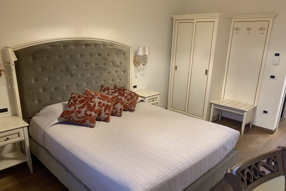Un dormitorio con una cama grande, una mesita de noche, un armario y una silla.