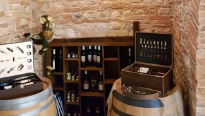 Une cave à vin aux murs de pierre, avec des barriques en bois et des étagères remplies de bouteilles de vin.