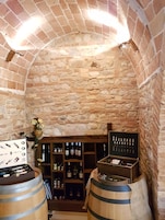 Una bodega rústica de paredes de piedra con barriles de madera y estantes llenos de botellas de vino.