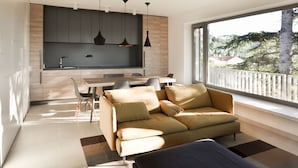 Un espacio de estar moderno con sofá, mesa de comedor y zona de cocina.