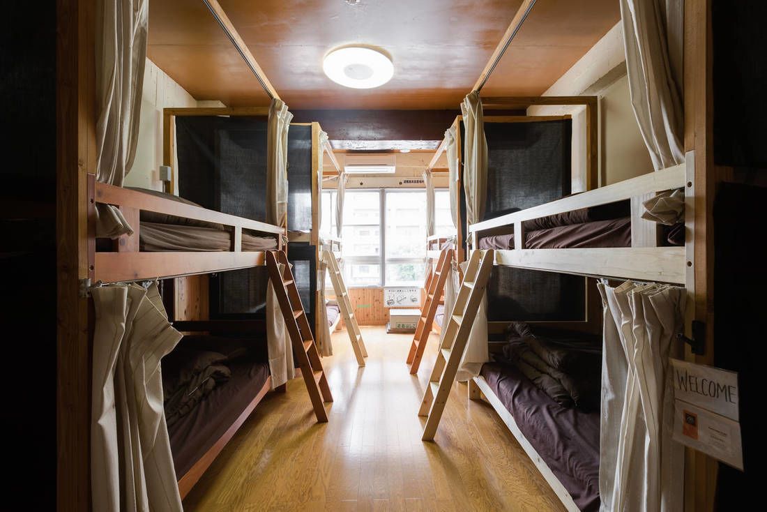 A bunk room with wooden bunk beds, a welcome sign, and a window providing natural light.
