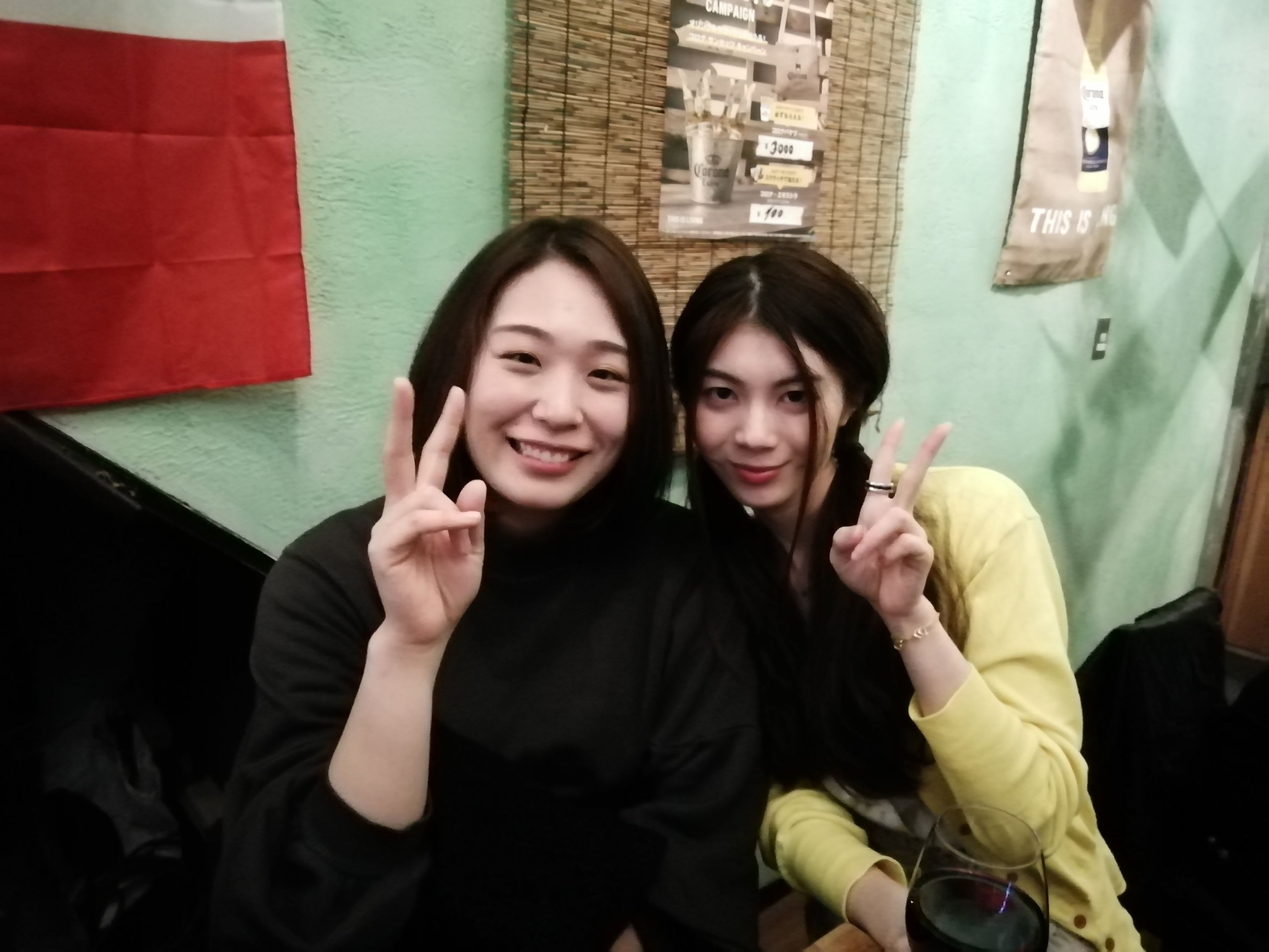 Two people sitting next to each other, making peace signs.