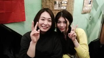 Two people sitting next to each other, making peace signs.