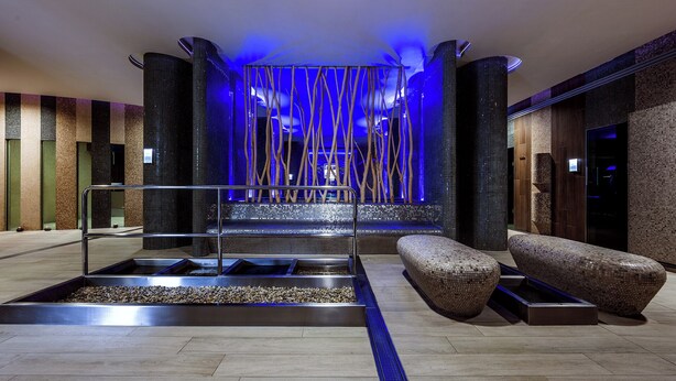 A modern lobby with a central seating area, a water feature, and a unique ceiling design. - Hotel Jezerka (Sec)