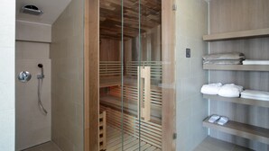 A modern shower enclosure with a glass door, a built-in shelf with towels, and a showerhead on the wall. - Hotel Jezerka (Sec)