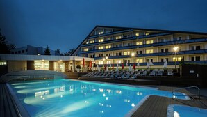 A hotel with a swimming pool, multiple floors, and outdoor seating with umbrellas. - Hotel Jezerka (Sec)