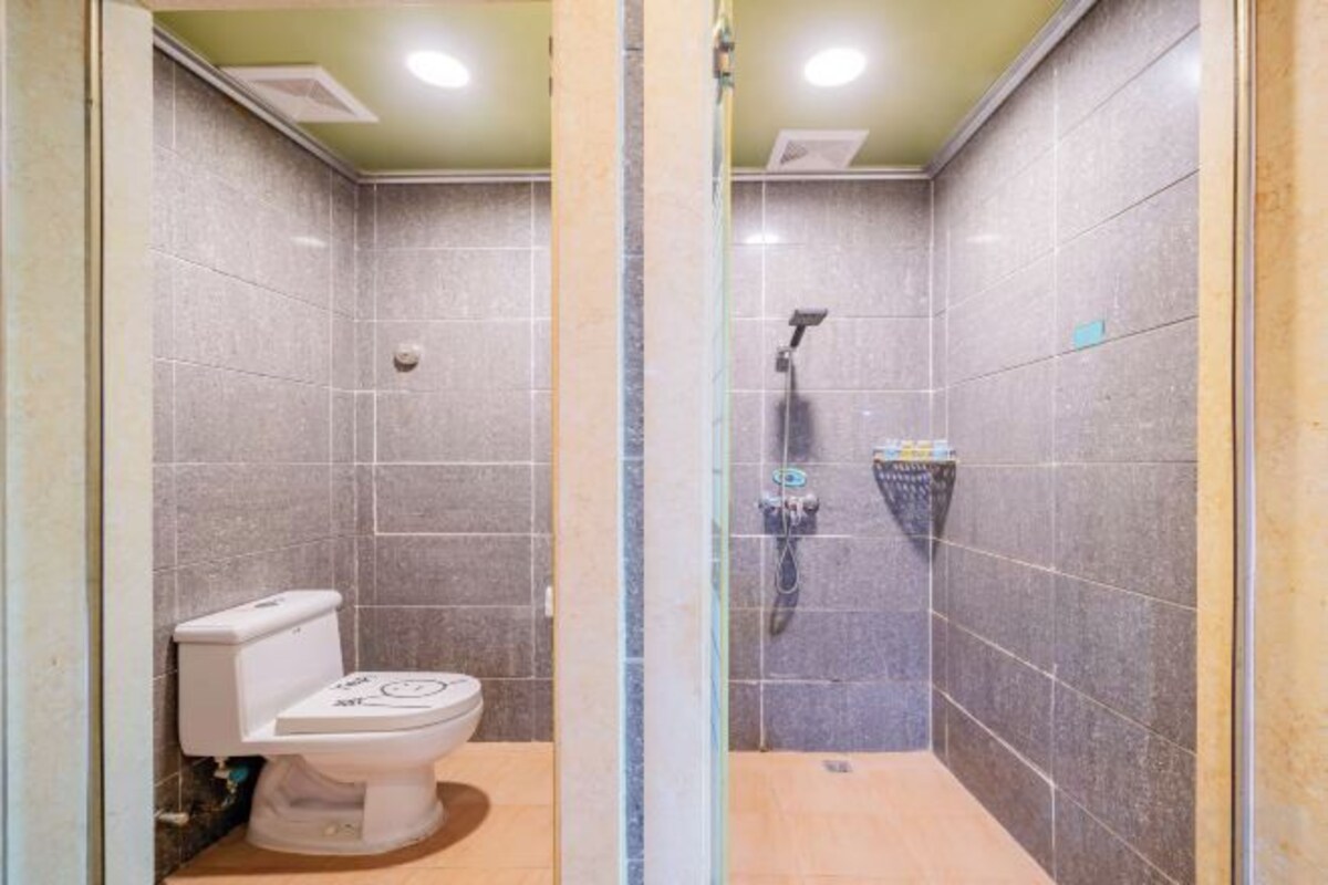 A bathroom with a toilet, a shower, and tiled walls.