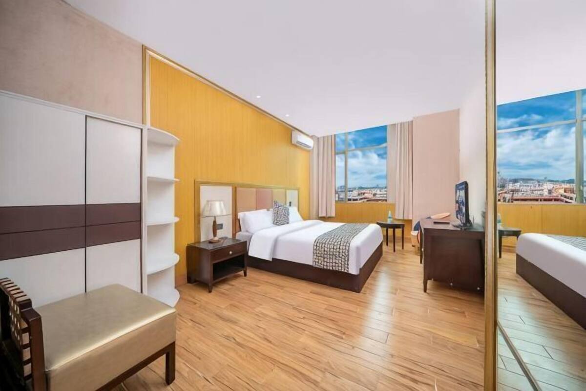 Habitación de hotel con cama, mesita de noche, lámpara y vistas a la ciudad.