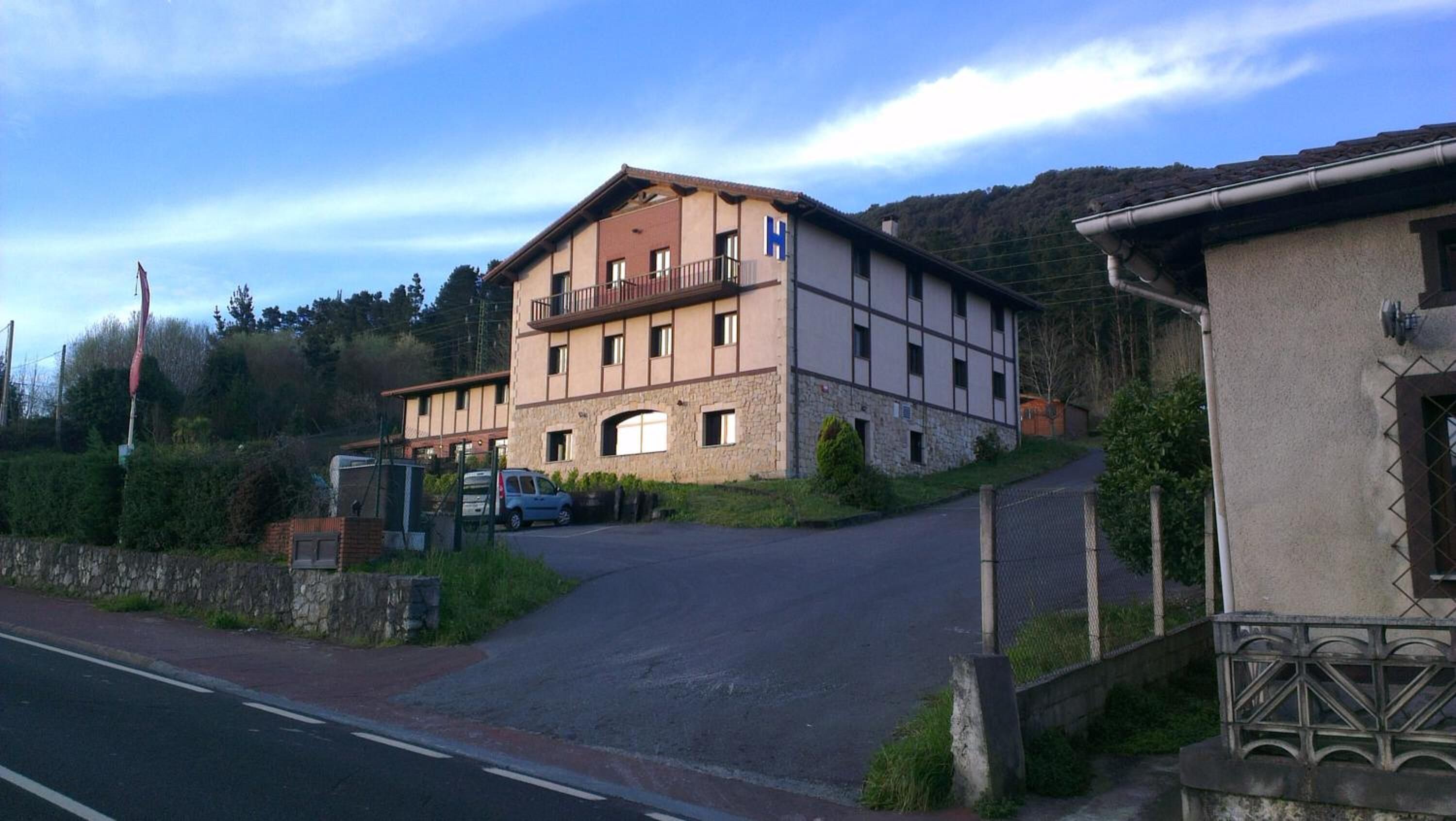 Un edificio de dos pisos con fachada de piedra, un balcón en el nivel superior y una entrada visible.