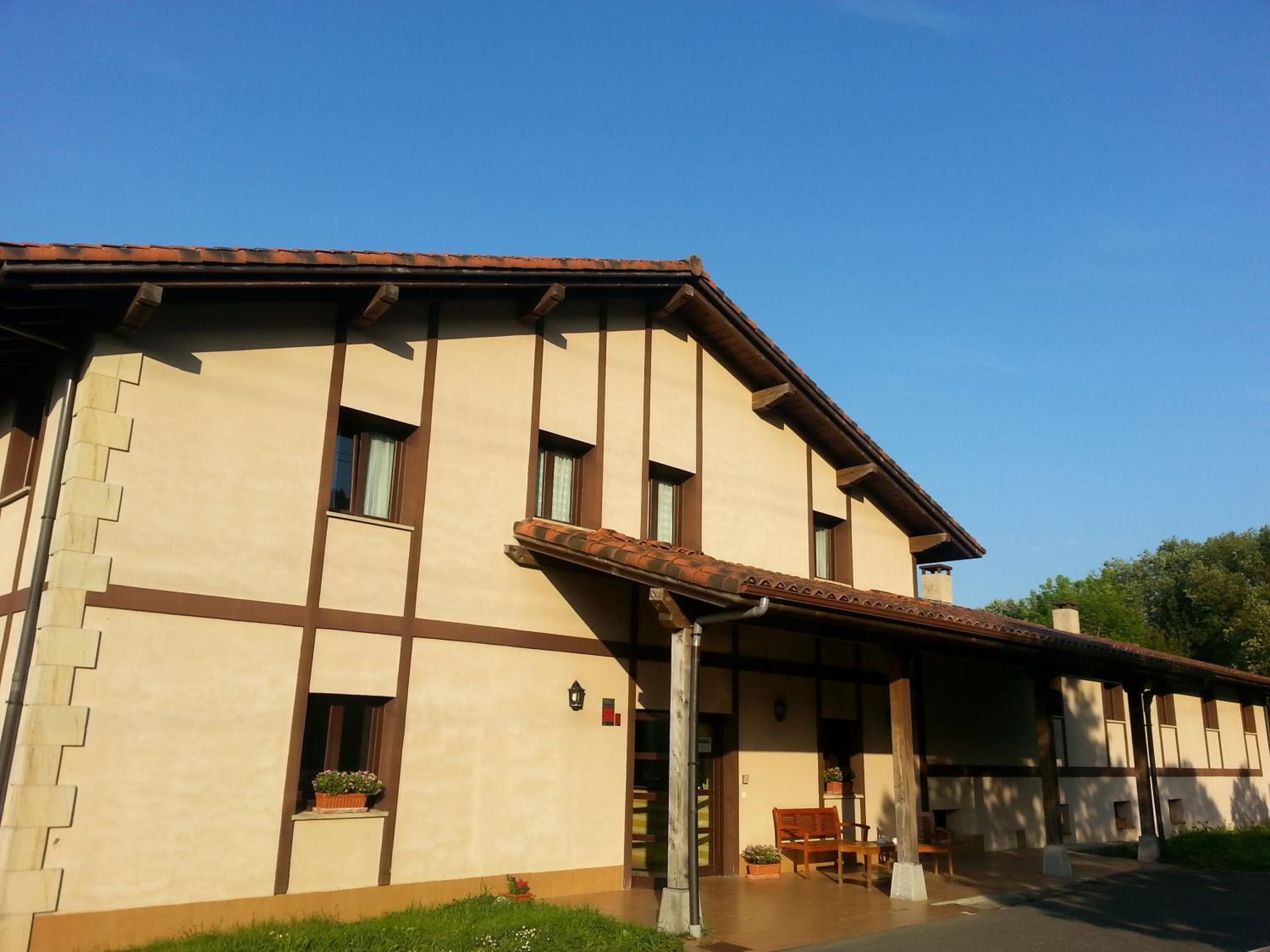 A building with a flat roof, large windows, and a covered entrance area with outdoor seating.