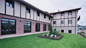 A modern building with a flat roof, large windows, and a well-maintained lawn. - Hotel Ibaigune (Murueta)