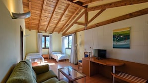A cozy room with a wooden ceiling, a sofa, a small table, a bed, and a TV. - Hotel Ibaigune (Murueta)