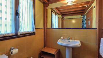 Un baño con techo de madera, un lavabo, un inodoro y una zona de ducha.