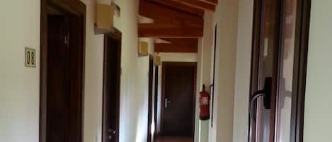 A hallway with wooden beams, doors, and a fire extinguisher.
