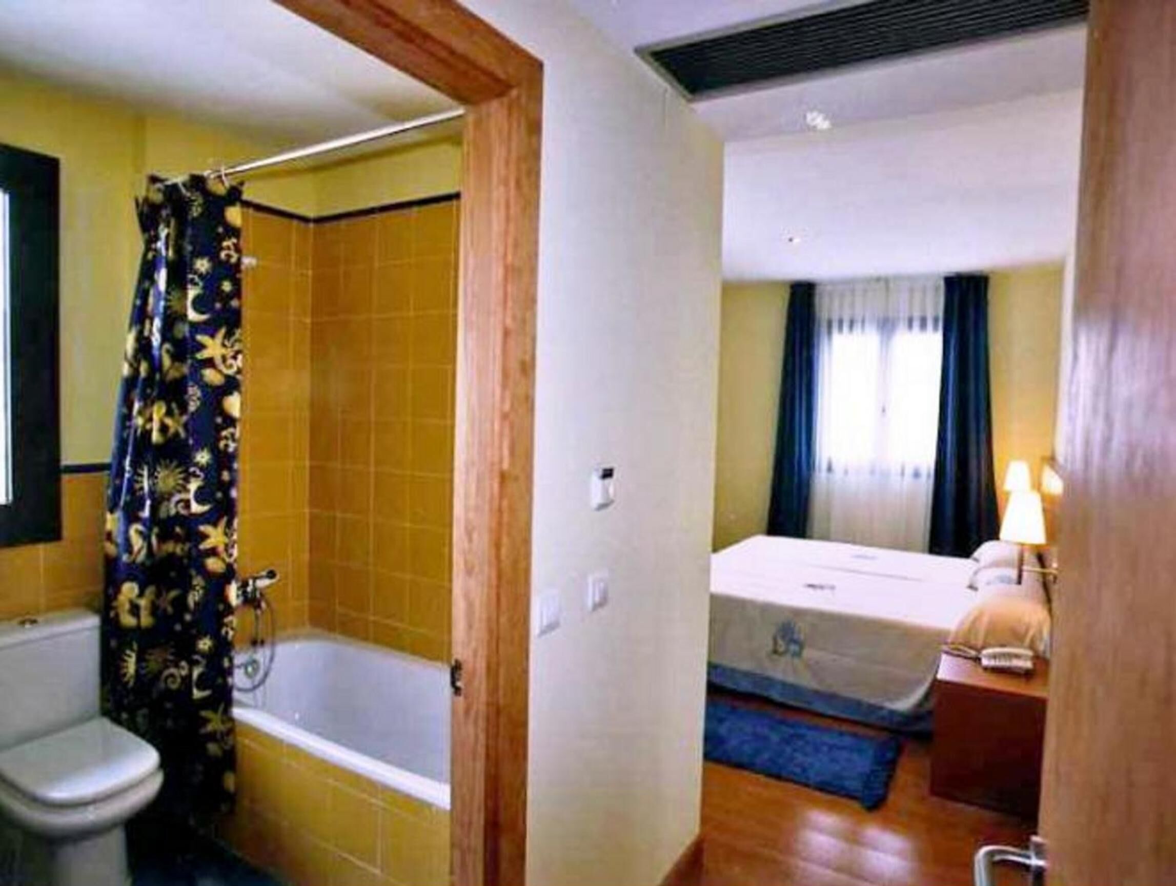 Un baño con bañera, inodoro y cortina de ducha.