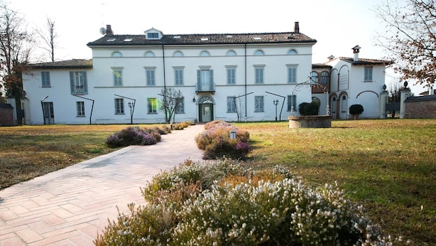 Ein großes, weißes Gebäude mit symmetrischer Fassade, einem zentralen Eingang und einem gepflasterten Weg davor.