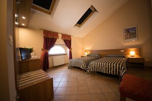 A bedroom with two beds, a desk, a chair, a radiator, and a window with curtains. - Locanda Ca' Rossa (San Giovanni in Croce)