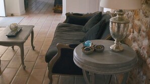 A living room with a sofa, a small table with a lamp, and a stone wall. - Mas Roussillon (Roussillon)