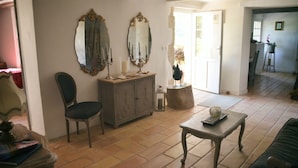 A living room with a chair, a table, and a cabinet. There are two mirrors on the wall. - Mas Roussillon (Roussillon)