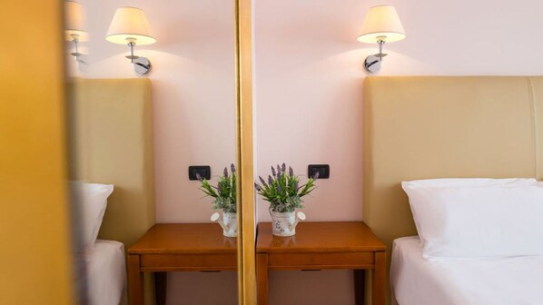 A mirrored room with a bed, two bedside tables, lamps, and a potted plant. - Center Hotel (Trieste)