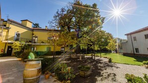Un patio con un árbol grande, un barril de madera y un edificio con un balcón.