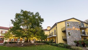 Un hotel con fachada amarilla, detalles de piedra y un balcón con pilar de piedra.