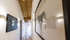 Un couloir avec des poutres en bois, des œuvres d’art encadrées accrochées aux murs et un éclairage encastré.