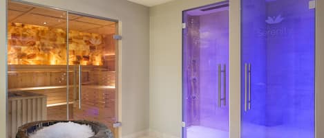 A modern spa room with a sauna, a glass-enclosed steam shower, and a stone basin.