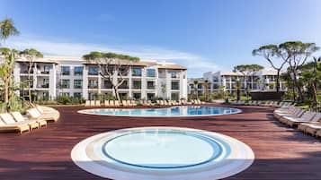 A resort with a large pool, sun loungers, and a building with multiple balconies.