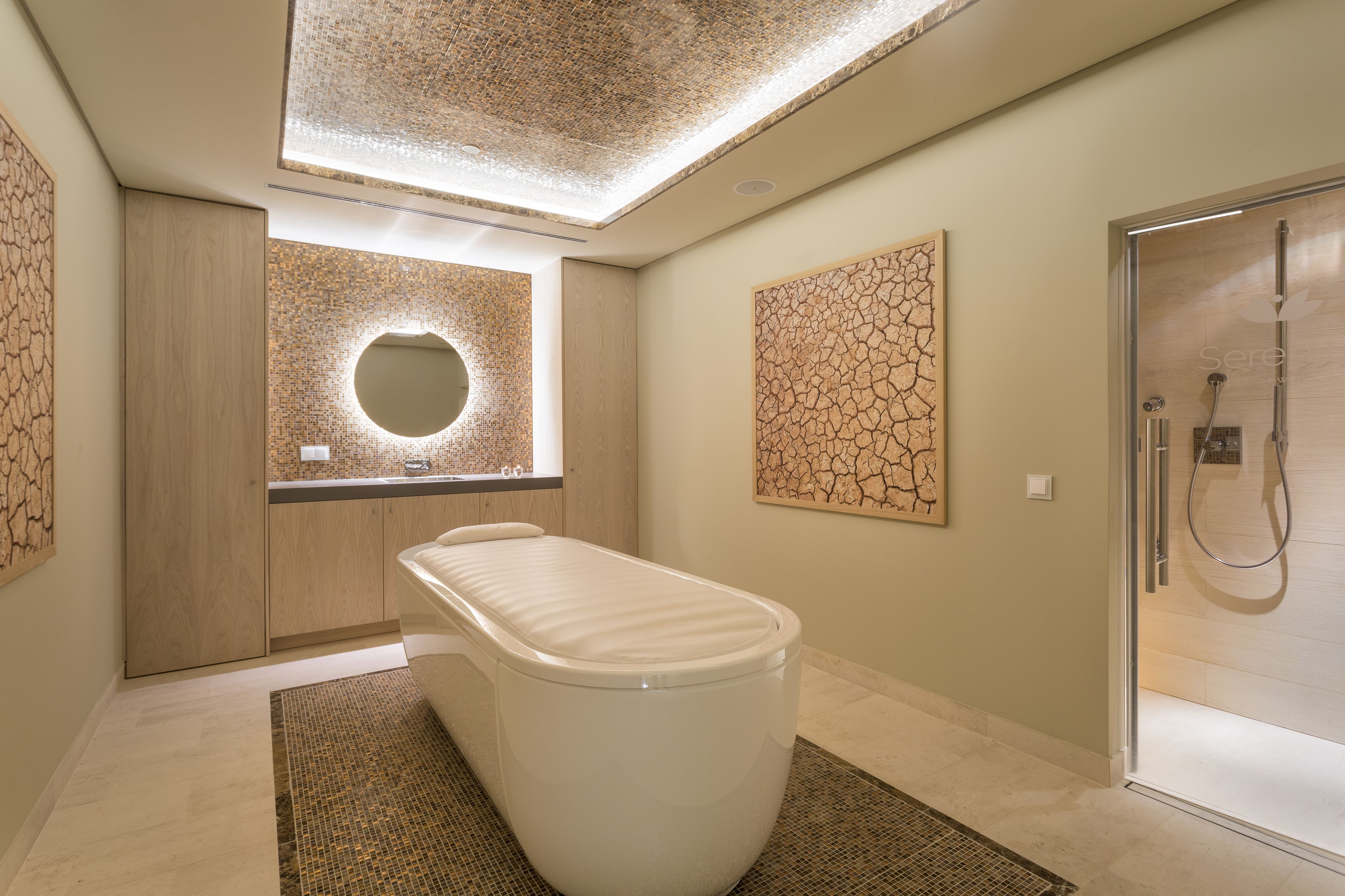A modern bathroom with a freestanding bathtub, a glass shower enclosure, and a skylight ceiling.