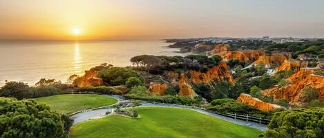 A coastal landscape with a grassy area, a winding path, and rocky cliffs.
