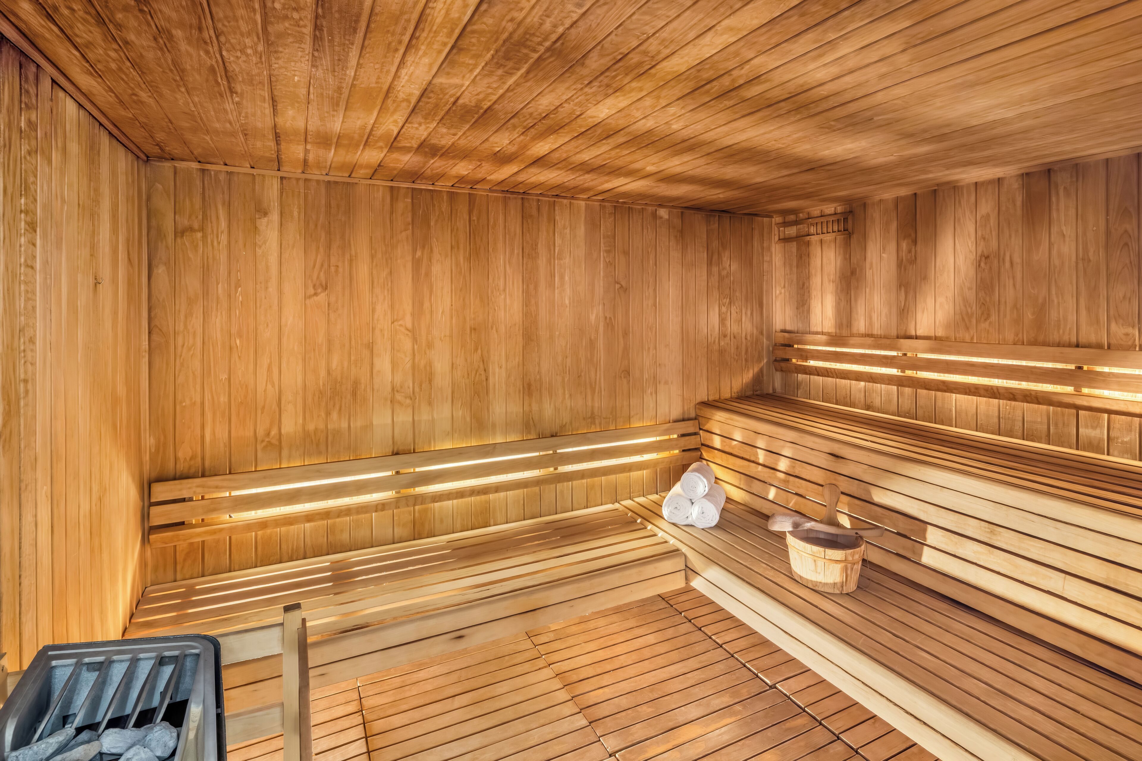 Eine Holzsauna mit Bänken, einem Eimer und einem Mülleimer.
