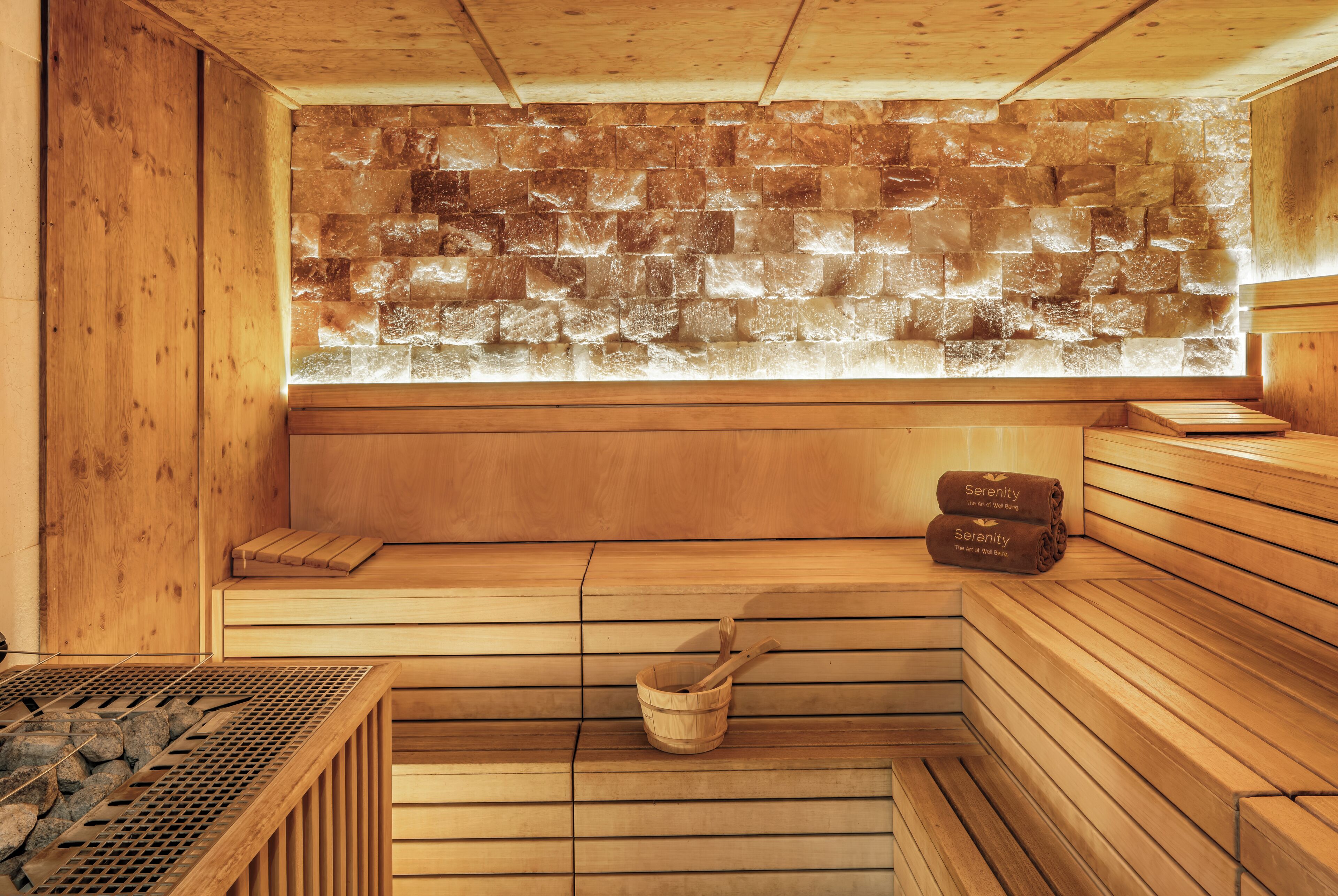 Una sauna con bancos de madera, pared de piedra y una ventana.