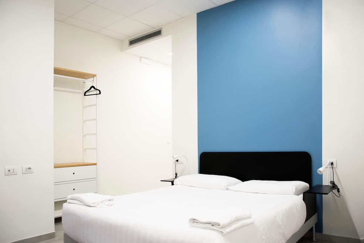 A bedroom with a bed, bedside tables, a wardrobe, and a mirror.