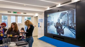 Un interior moderno con una pantalla grande mostrando una escena histórica de la calle, una barra de bufé y letreros de salida visibles.