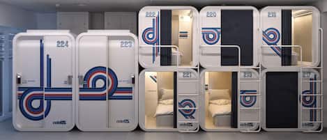 A row of connected hotel rooms with numbers 221 to 224, each with a bed, a small table, and a chair.