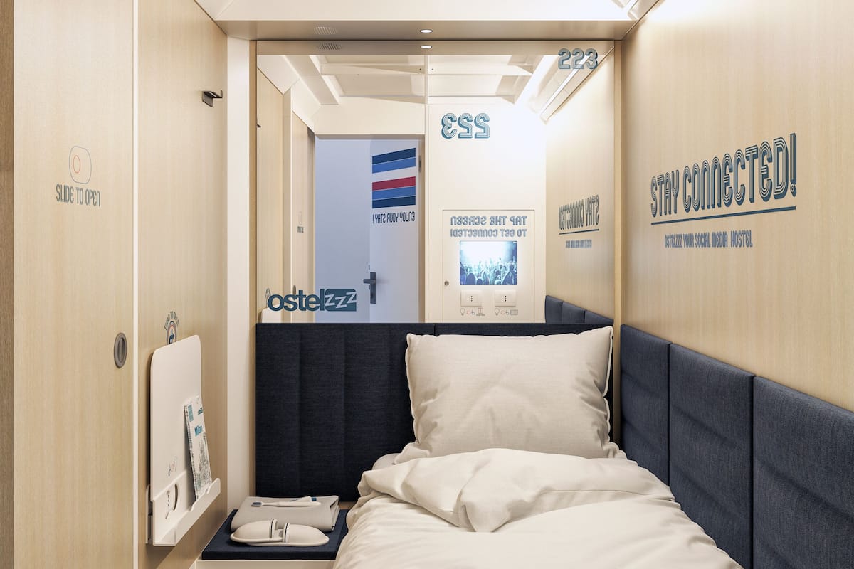 A compact hotel room with a bed, a small bedside table, and a wall-mounted TV.