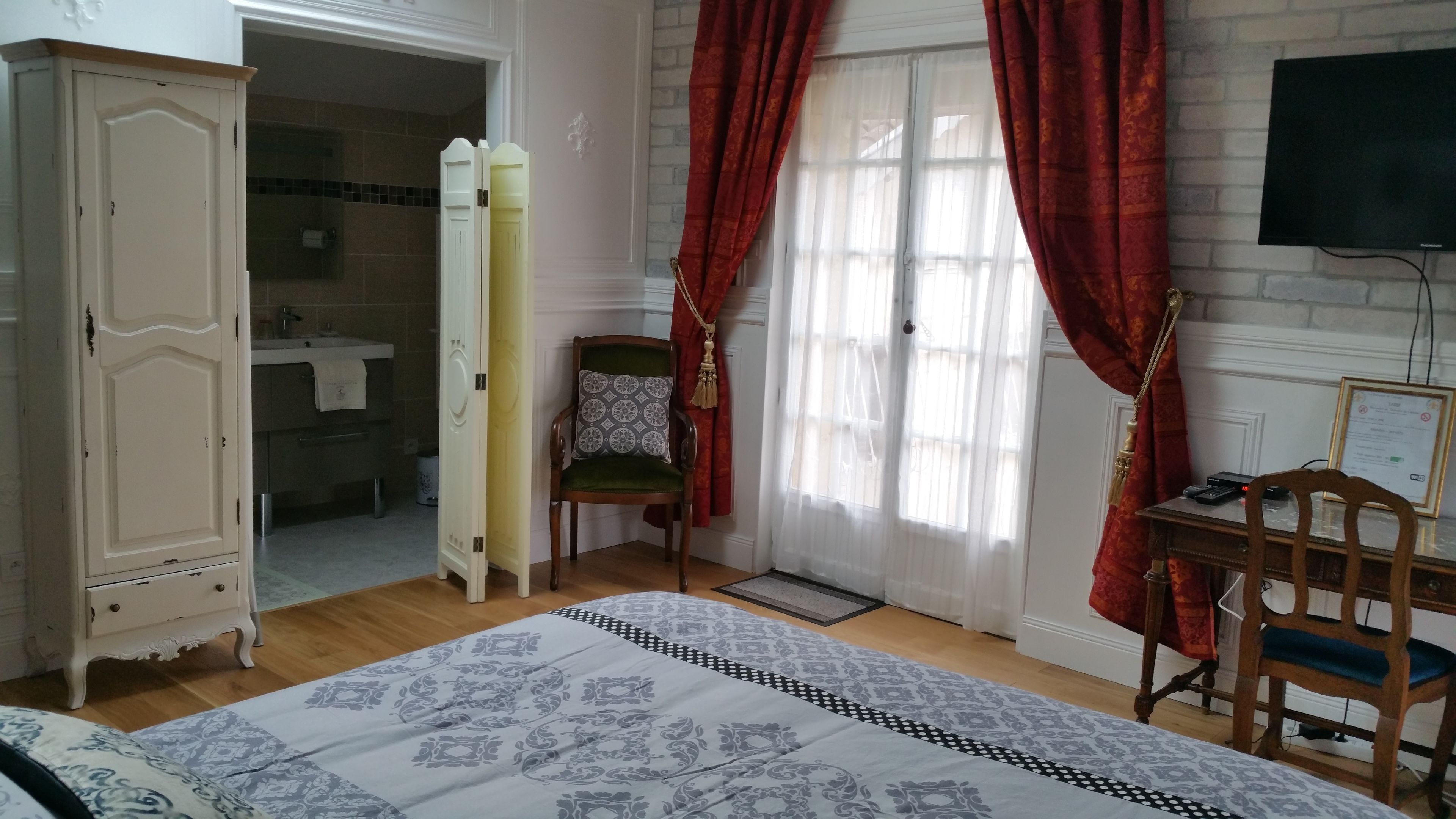 A bedroom with a bed, a wardrobe, a chair, a desk, and a television.