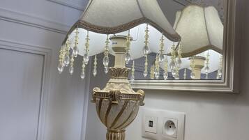 Una lámpara decorativa con pantalla blanca y cuentas de cristal sobre una mesa con intrincados relieves.