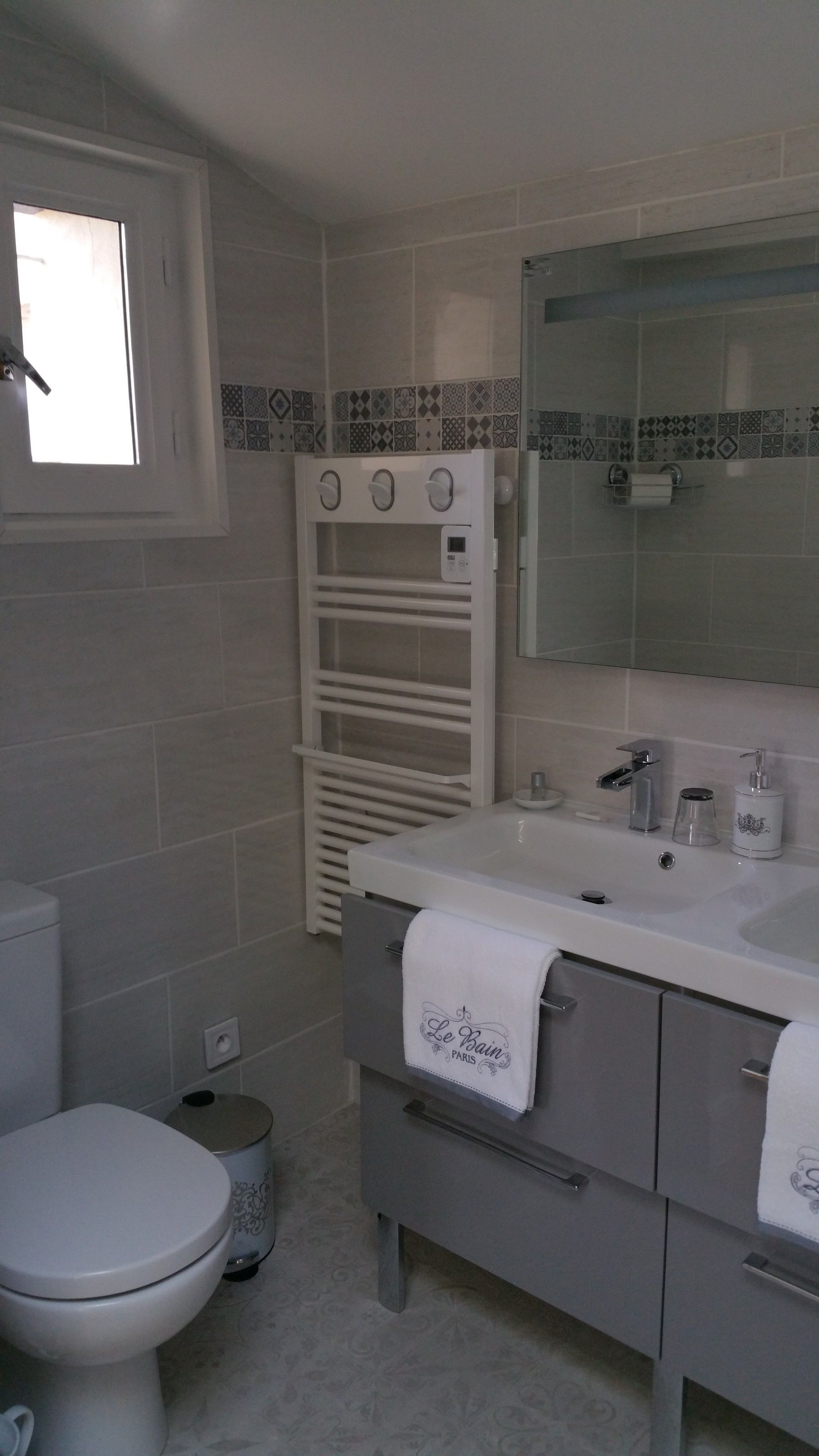 A bathroom with a toilet, a sink, a mirror, and a towel rack.