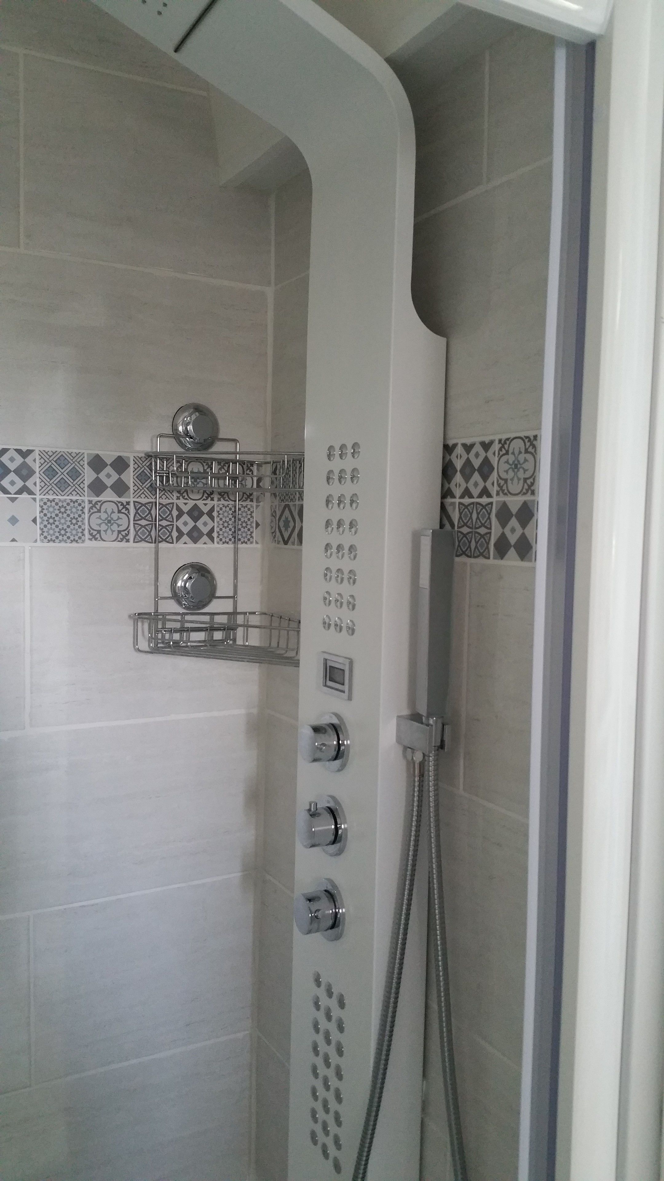 Douchecabine met bedieningspaneel, handdouche en wandmengkraan.
