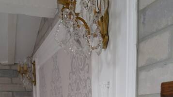 Quarto com cama, lustre, cabeceira de madeira e papel de parede estampado.