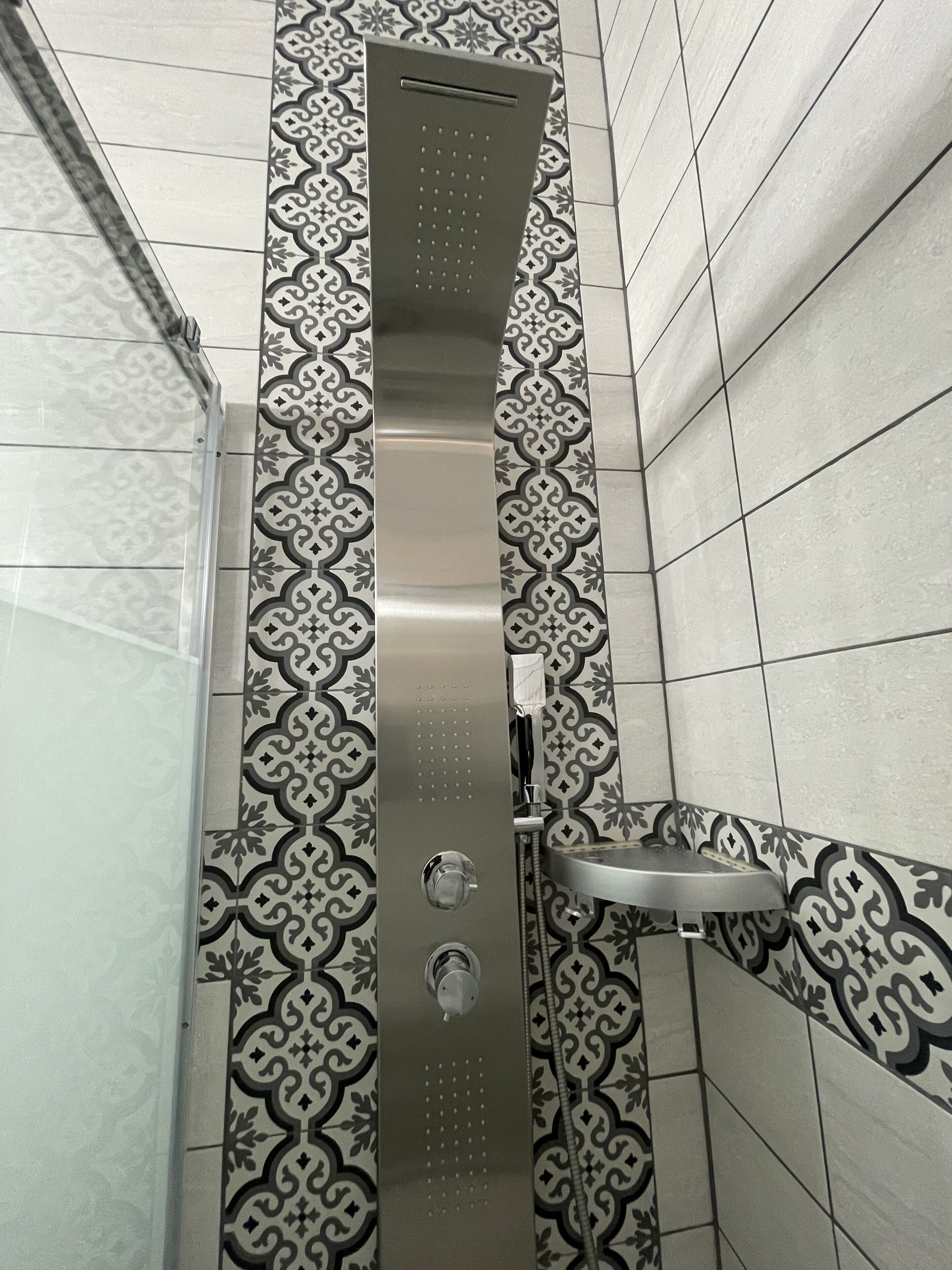 A shower area with a patterned tile backsplash and a metal showerhead.