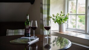 A table with a bottle and two wine glasses, a magazine, and a potted plant by a window. - Bearslake Inn (Okehampton)