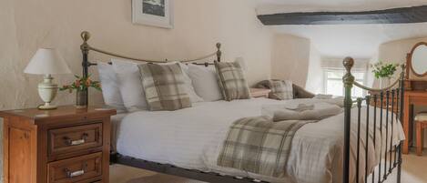 A bedroom with a bed, wooden nightstand, and a mirror.