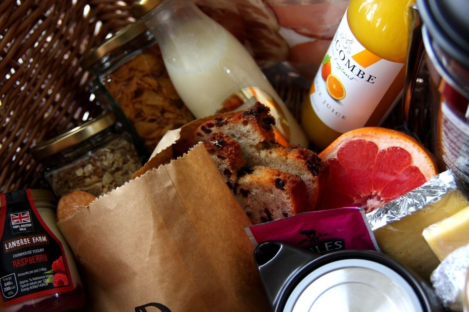 A variety of food items including bread, a bottle of juice, and a container of yogurt.