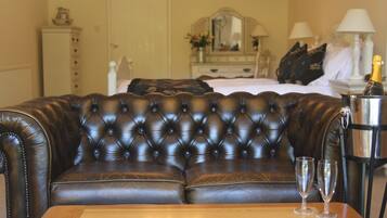 A dark brown leather sofa with a tufted backrest, a wooden table with two clear glasses, and a metal container with a bottle.