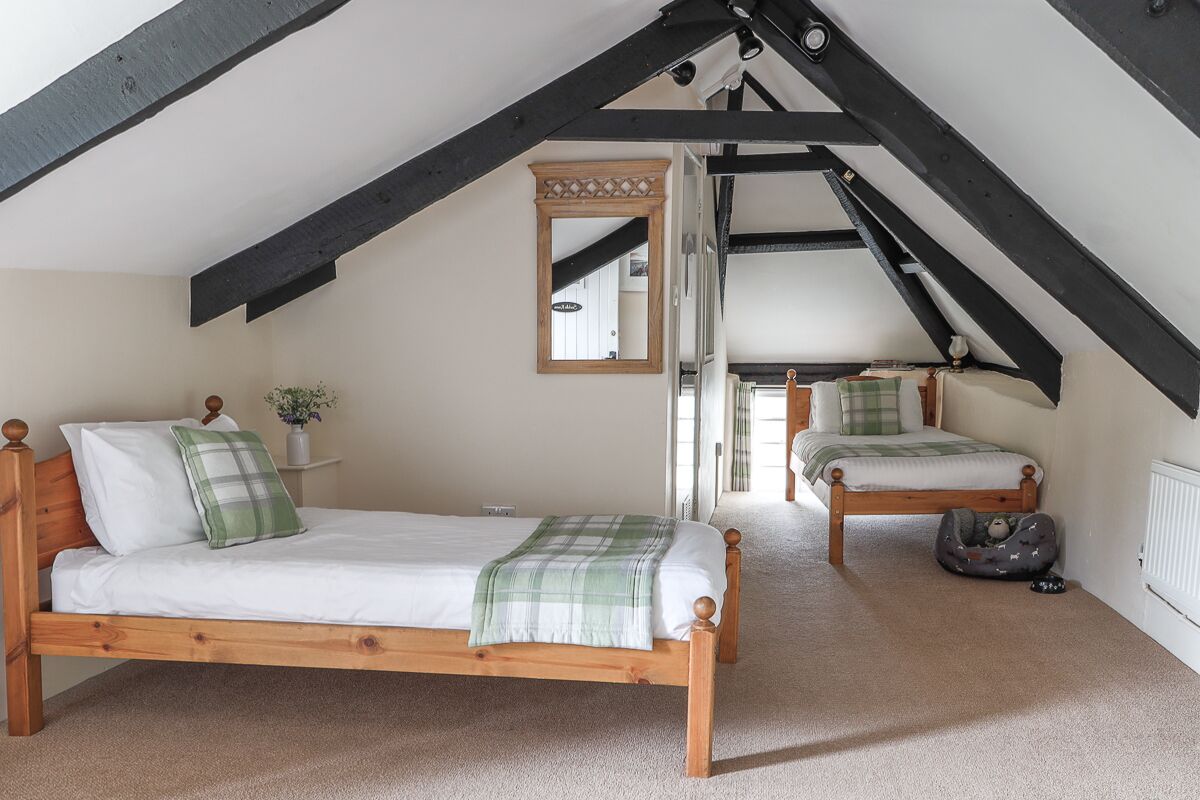 Une chambre à coucher avec deux lits en bois, un miroir et un radiateur.