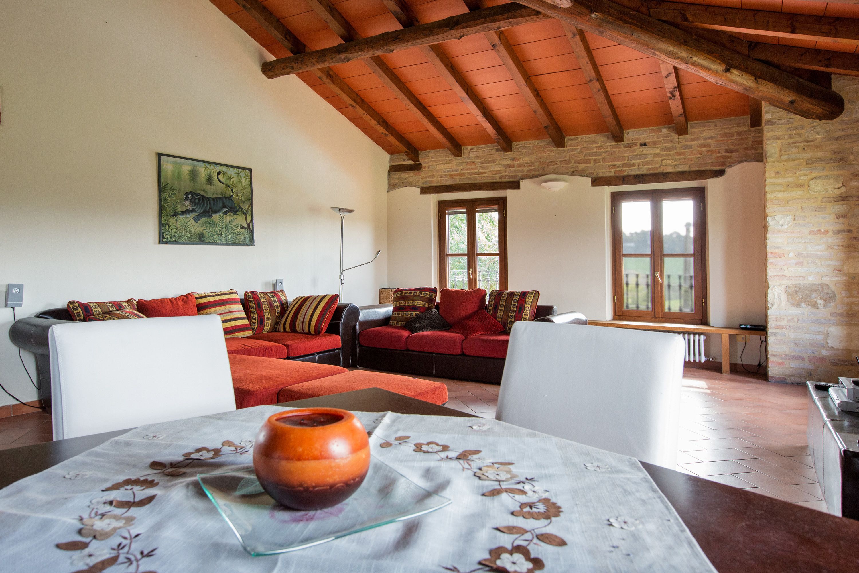 A living room with a high wooden ceiling, a sofa set, and a table with a vase.